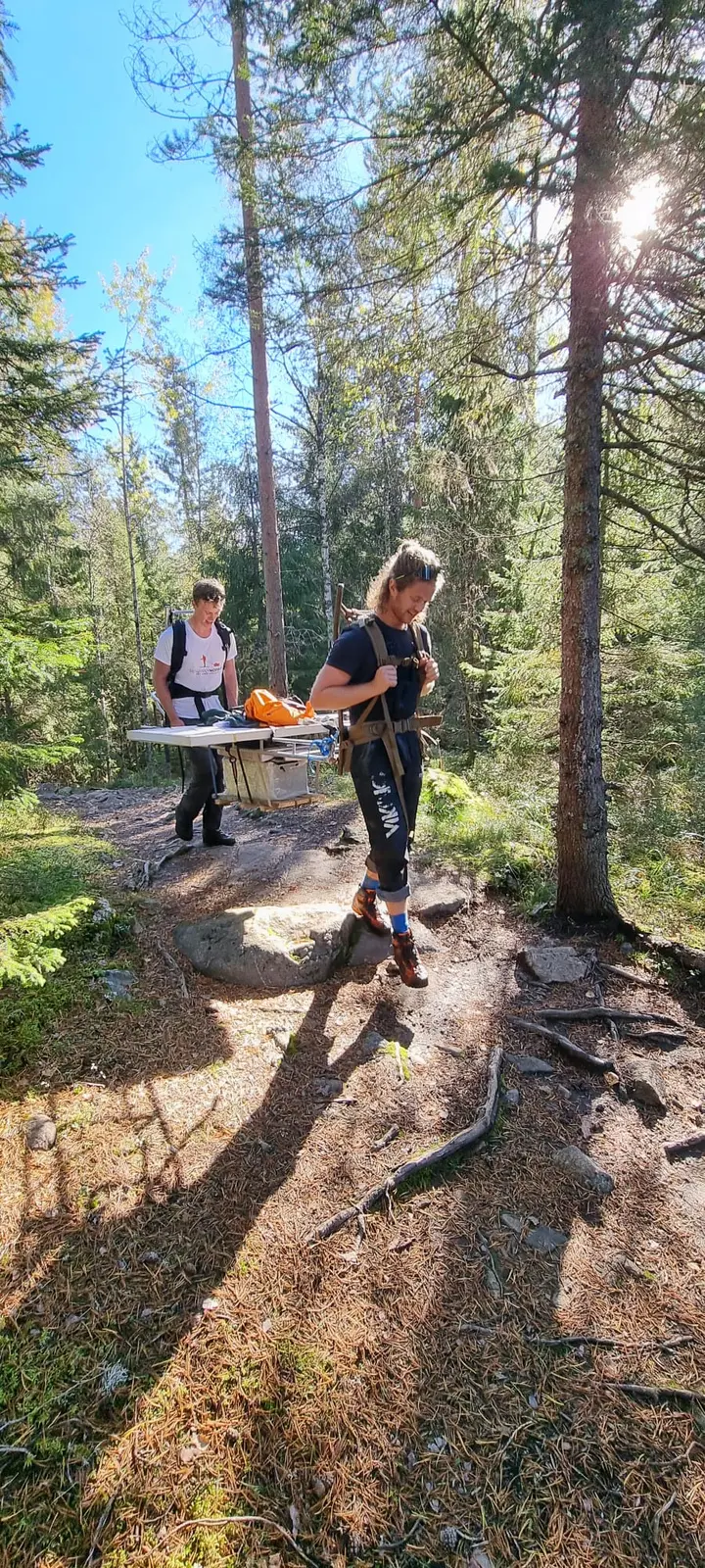 To personer frakter tungt teknisk utstyr med spesialbåre