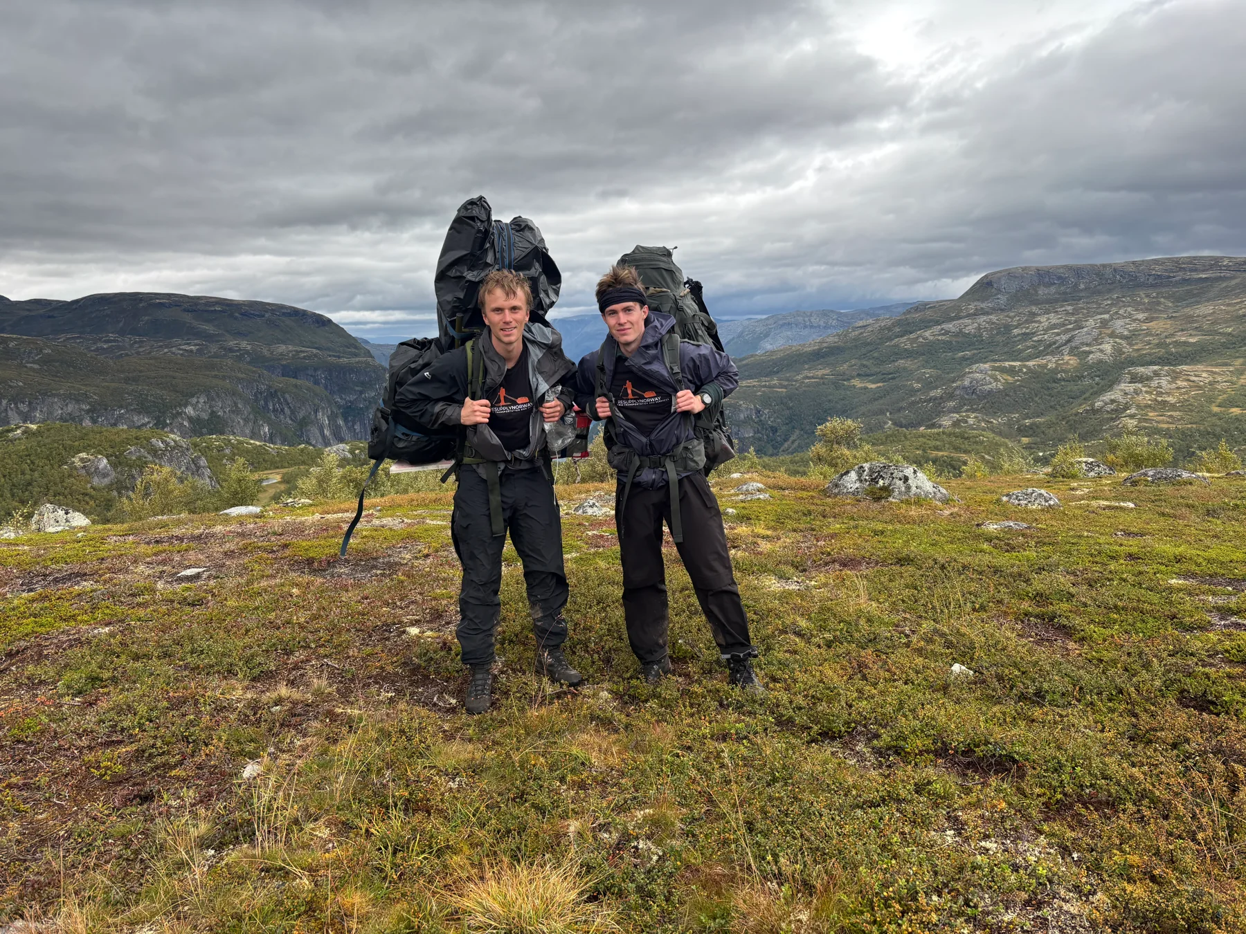Two people carrying loads across Hardangervidda