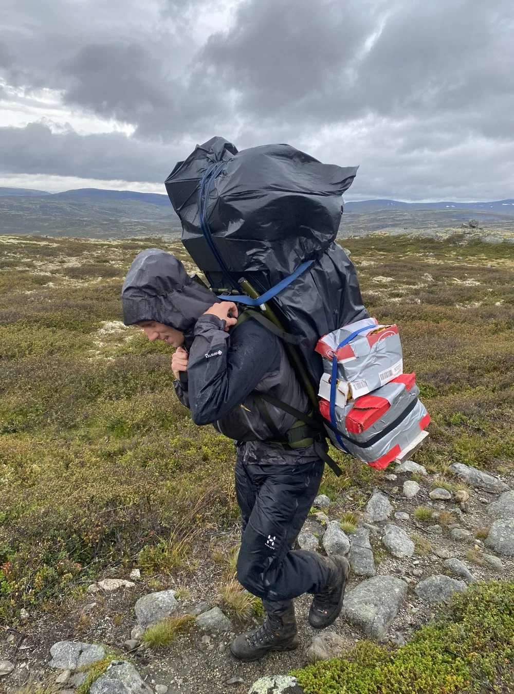A person carrying a heavy load in open mountain terrain